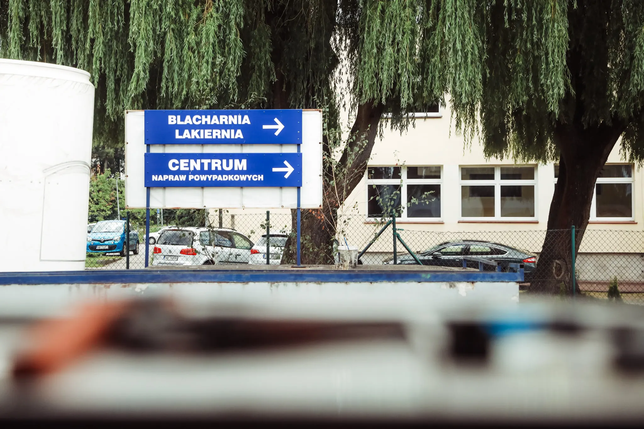 Drogowskazy „Blacharnia lakiernia" i „Centrum napraw powypadkowych" przed Auto Brudniewicz