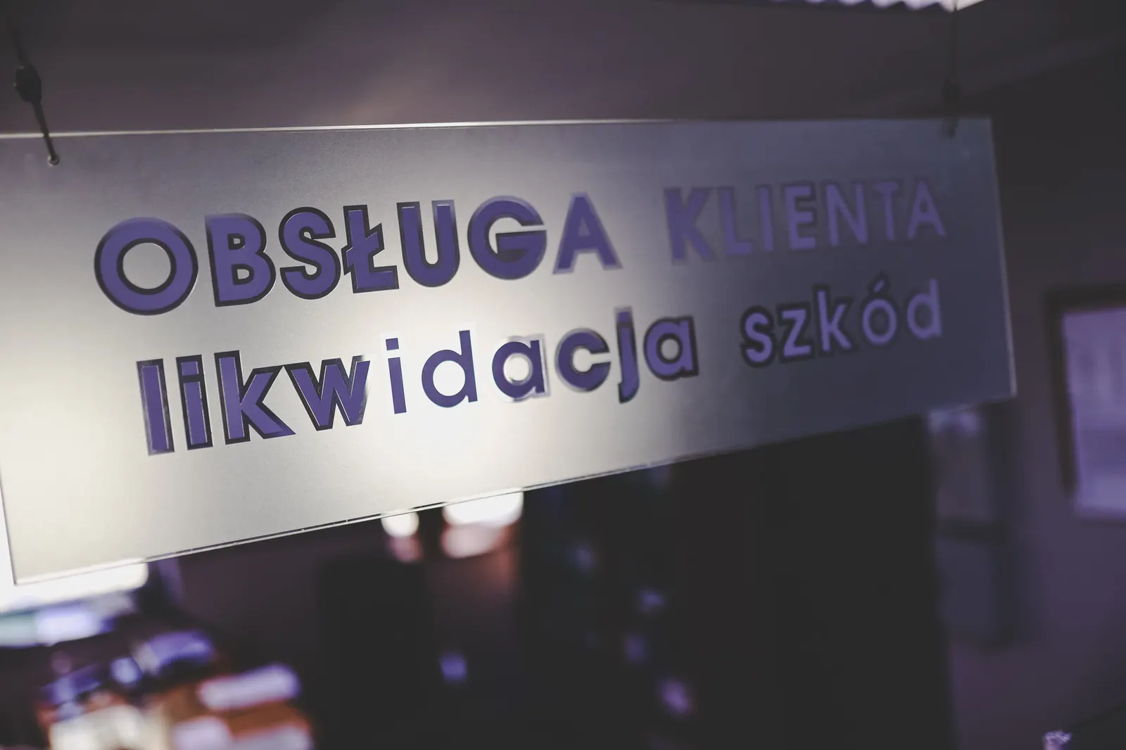 Szyba z napisem „Obsługa klienta, likwidacja szkód" w biurze Auto Brudniewicz